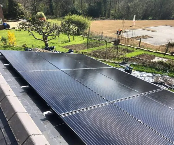 Ground-mounted solar panel array in a landscaped garden with rural surroundings