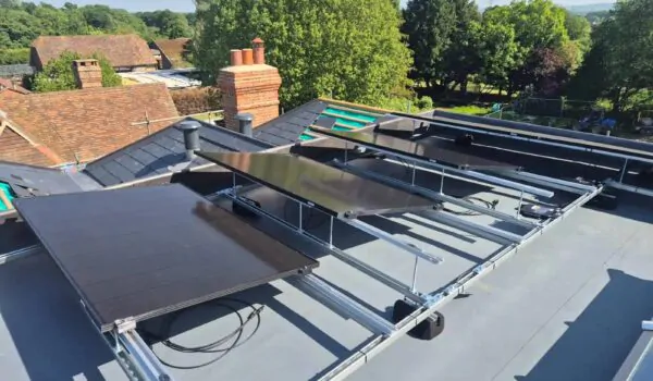 Ground-mounted solar panel array in a landscaped garden with rural surroundings