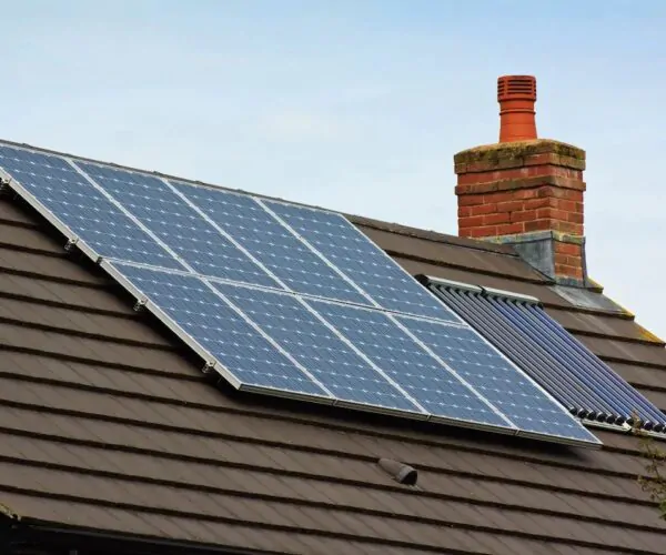 Pitched roof installation of photovoltaic (PV) panels alongside solar thermal tubes on a residential property in Sussex.